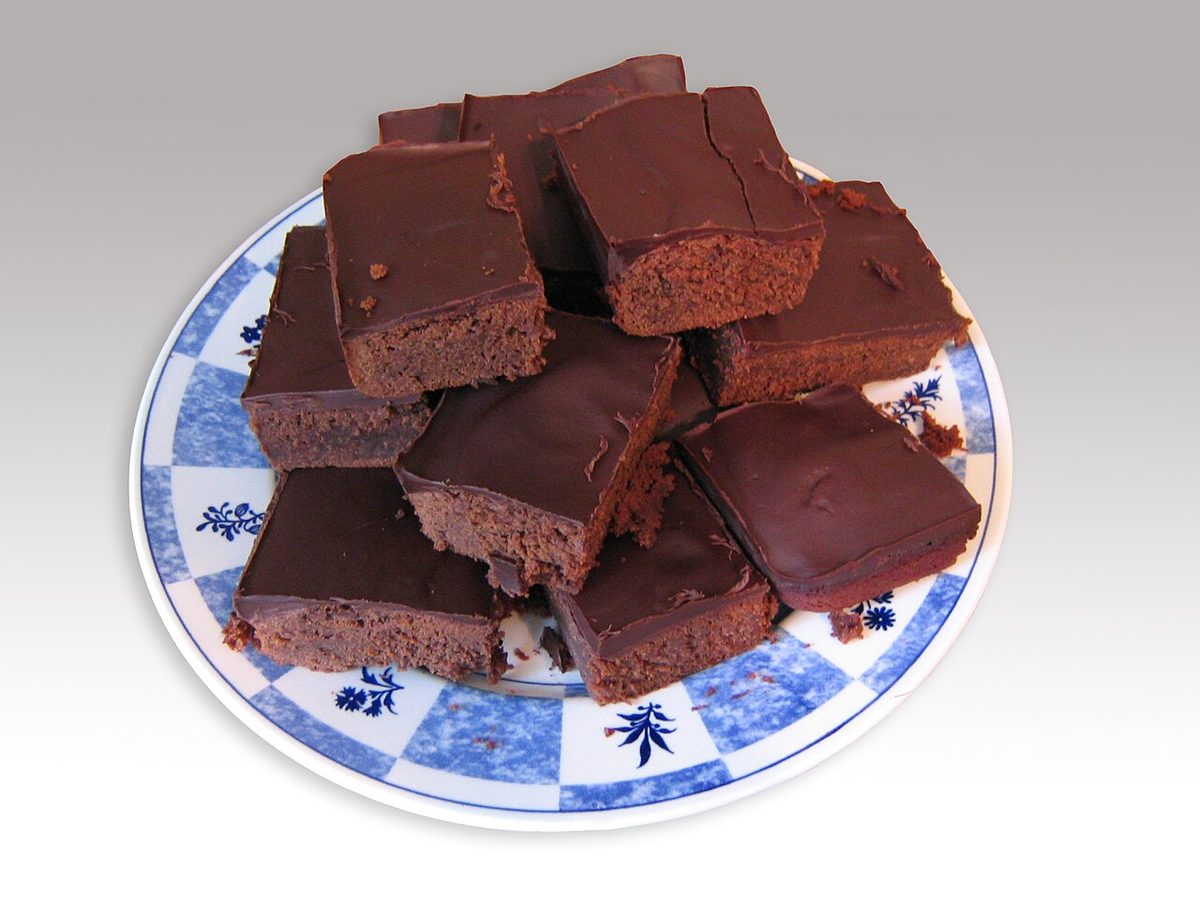 Kawałki czekoladowego brownie z błyszczącą polewą ułożone na talerzu w niebieskie wzory