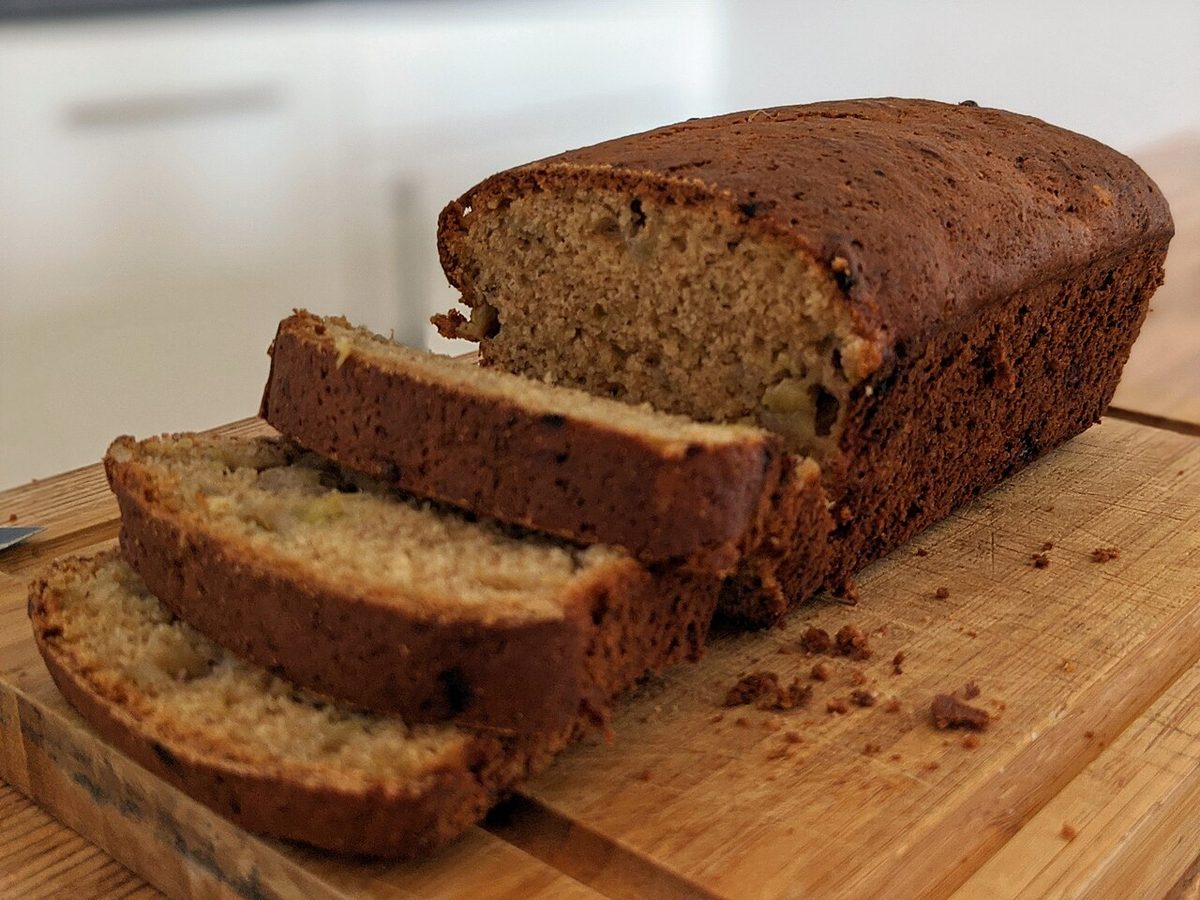 Pokrojony chlebek bananowy z kawałkami orzechów na drewnianej desce