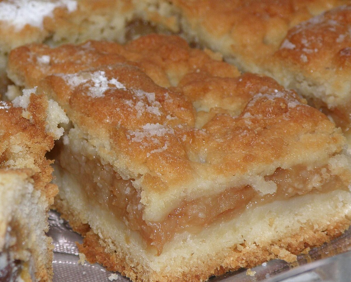 Kawałki szarlotki z grubą warstwą jabłek i kruszonką oprószoną cukrem pudrem