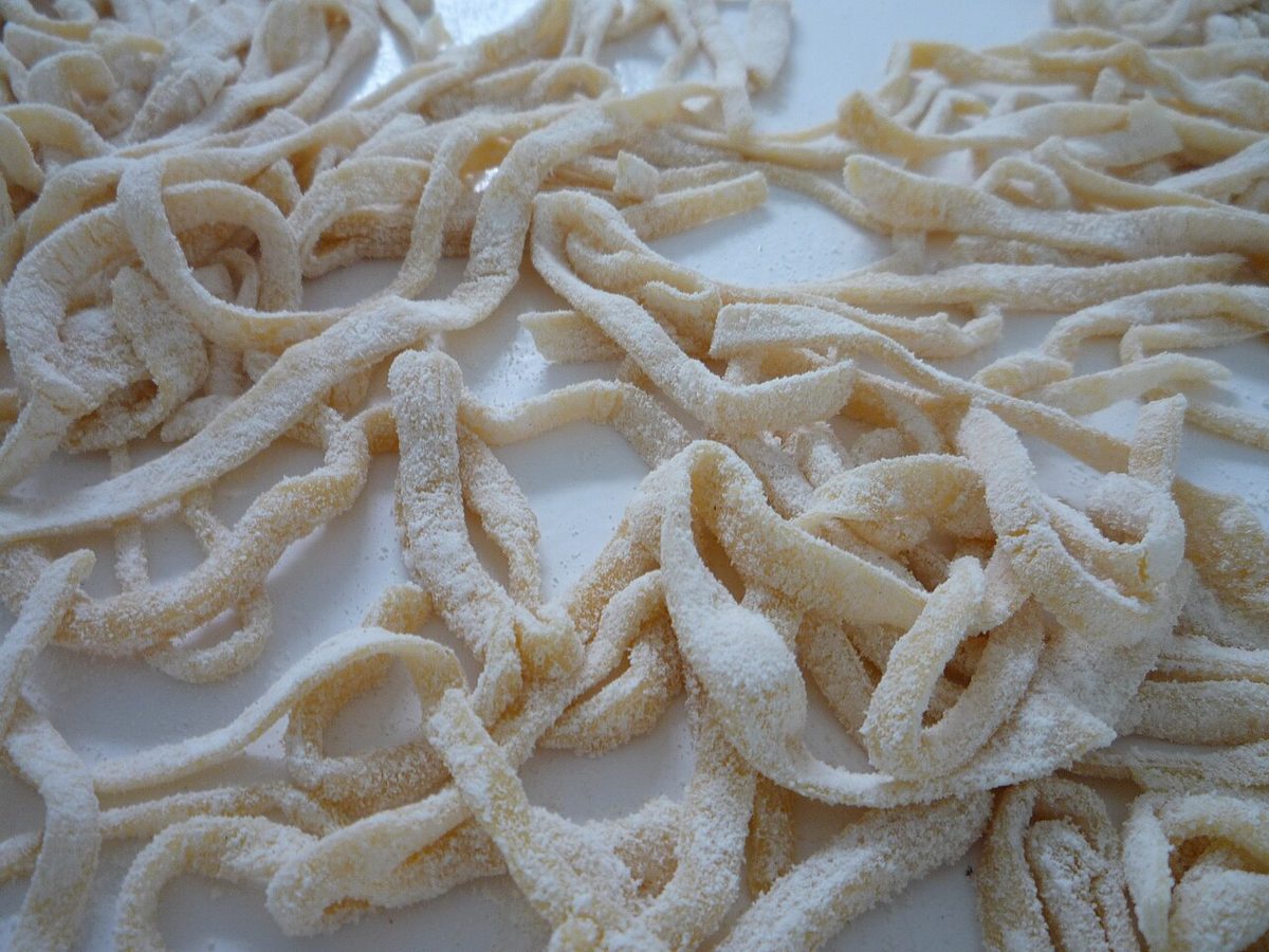 Świeżo pokrojone domowe tagliatelle oprószone mąką na blacie