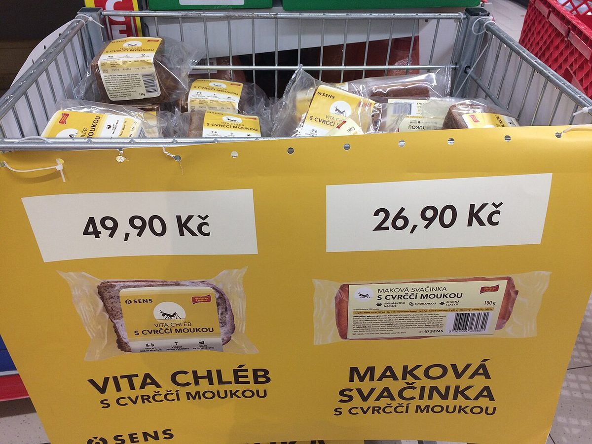Kosz w supermarkecie z chlebem i przekąskami z mąką ze świerszczy, z żółtymi etykietami cenowymi